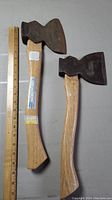 Two single bevel hatchets laid flat with a ruler beside them for size reference showing the old axe heads with new handles.