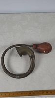 Full view of brass horn lying flat showing circular, curved brass tube with attached rubber squeeze bulb.