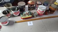 Full view of all vintage tins arranged on a table, showing multiple brands including York Peanut Butter, Imperial Sugar Cream Butter, honey tins, and Planters salted peanuts
