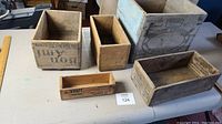Five wooden boxes of varying sizes and branding laid out on a table, showing overall lot contents.