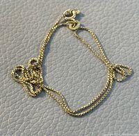 Close-up of the clasp showing the chain details and gold marking.