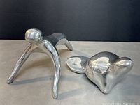 Two polished aluminum sculptures by Hoselton Canada, showing overall form and size with one sculpture on all fours leaning forward and the other in a rounded reclining pose.