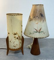 Full front view of two Mid-Century Modern tripod rocket style table lamps with botanical printed shades, showing overall condition and detailing.