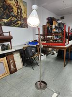 Full view of lamp in storage room showing base, stem, adjustable arm, and shade