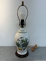 Full view of Portmeirion Botanic Garden table lamp showing the lamp body, bulb, harp, and wooden base.