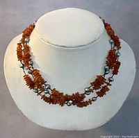 Front view of the vintage 3-strand natural amber necklace displayed on a white bust, showing the amber chips and silver beads detail.
