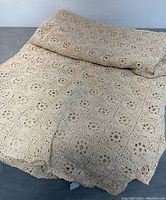 Folded vintage hand-crocheted bedspread laid on a flat surface showing overall pattern and color.