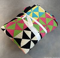 Folded view of quilt showing folded pattern and tied with white ribbon.