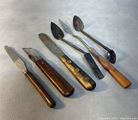 Set of six vintage pottery and clay sculpting tools laid out on a surface, showing overall shape and condition.