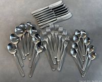 Full set of cutlery including knives, forks, teaspoons, and tablespoons arranged on a surface.
