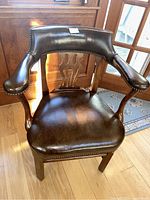 Front view of Baker Furniture wood chair with dark brown leather seating and carved wooden backrest details.