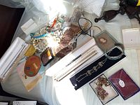 Overview of assorted costume jewelry laid out on a surface, including multiple necklaces, bracelets, and boxes