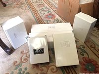 Photo of five white Mikasa-branded boxes on carpet with floral rug edge, indicating multiple Mikasa items boxed