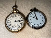 Photo of two pocket watches side by side, Westclox on left with ornate dial and Bullseye on right with simpler dial.