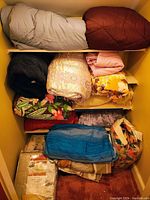 Shelves with rolled and folded blankets and quilts in various colors.
