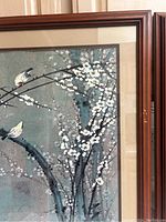 Close-up of top right corner of first framed print showing two birds on white blossoms with blue-gray background and dark branch, and part of frame