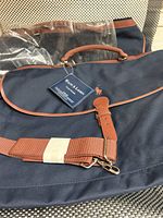 Two Ralph Lauren classic navy blue travel bags stacked with tags and plastic cover visible, showing exterior materials and straps.