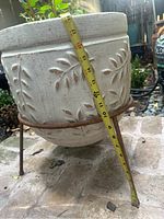 Close up of the large white pot showing embossed leaf design and measuring tape indicating height.