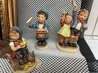 Photo showing all three Goebel children figurines together on a checkered background