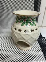 Front angled view of Lenox tea light candle holder, showing lattice pattern and holly motif around upper rim