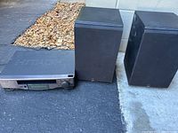 Hitachi FX624 stereo receiver and two Quart One speakers positioned outdoors on the ground, showing front and top of devices.