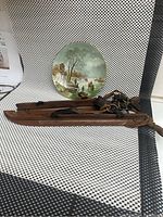 Photo showing vintage A Schelfhout winter landscape decorative plate with gold rim, and 19th century Coopday ice skates made of wood with leather straps.