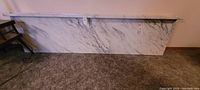 Two laminate countertops with white and grey marble pattern leaning against a wall on carpeted floor.