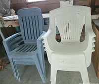 Three blue plastic stackable lawn chairs stacked together with visible fading and wear, no cracks.