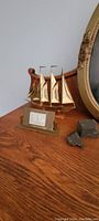 Brass ship desk clock with rectangular clock on wooden surface next to decorative rock pieces and a gold-framed mirror