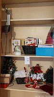 Shelf displaying multiple Christmas decorations including baskets with flowers, wooden deer figure, snow globe, and decorative boxes.