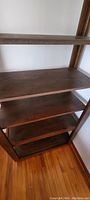 Close-up view of multiple shelves showing dark brown stained pine wood, highlighting adjustable shelf configuration.