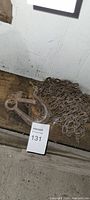 Used large metal chain coiled and attached to a heavy-duty metal hook with a latch, placed on a wooden surface near a wall.