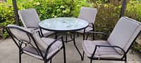 Full set showing round glass table and four metal frame chairs with cushions