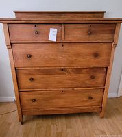 Front view of vintage pine dresser showing five drawers with round wooden knobs and keyholes.