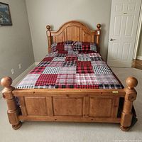 Front view of wood double bed with bedding and headboard visible