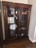 Full view of cabinet showing wooden frame and glass doors with decorative glazing bars.