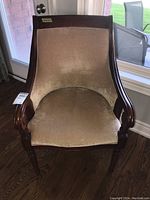 Front view of wood and upholstered chair showing beige fabric and curved wooden armrests