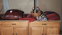 Photo showing all contents of lot including leather pillow, crochet blankets, wool blankets, wicker basket, thermos and sunglasses