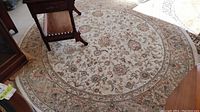 Photo of the entire round rug laid on the floor, showing floral patterns and colors.