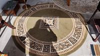 Full view of the round beige and black patterned rug on the floor with furniture around it.