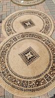 Two round beige and black rugs with Greek key and floral medallion pattern.