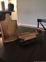 Photo showing both the wooden wall shelf and decorative sled on a table for size reference and details
