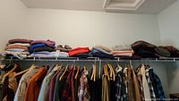 Photo of sweaters folded in stacks on a shelf with varied colors and knit textures.
