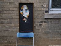 Full view of framed painting leaning against a brick wall