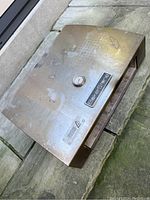 Top-down angled view of used BakerStone Grill Top Pizza Oven Box showing wear, built-in temperature gauge, and BakerStone logo plate on top surface.