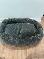 Dark gray large oblong dog bed with bolster sides and removable covers shown from above on wooden floor.