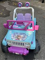 Front view of the Frozen Power Wheels Jeep showing seating, steering wheel, and Frozen graphics on the hood.