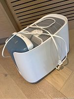 White Honeywell humidifier with blue water tank and power cord wrapped on top, side angle