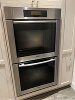 Front view of stainless steel double oven installed in cabinetry with digital control panel