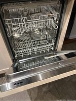 Open dishwasher door showing stainless steel interior tub and lower and middle racks.